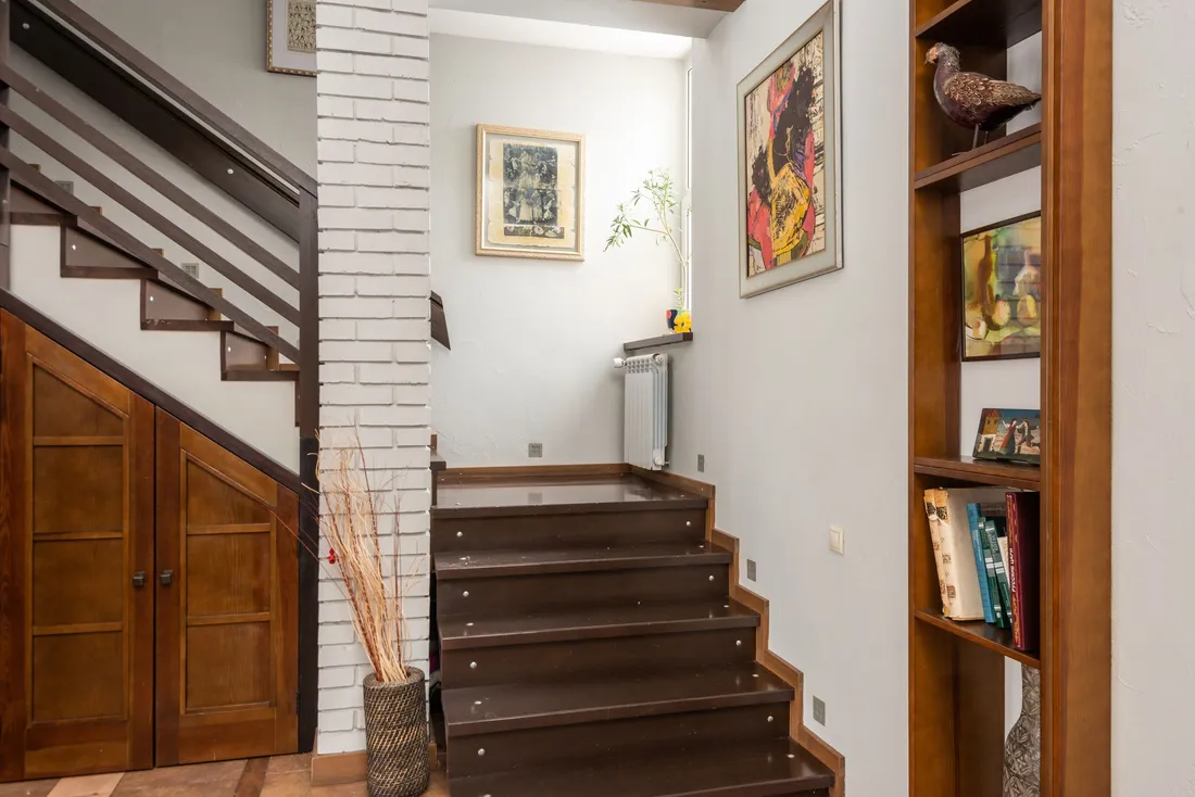 Escalier en bois qui monte à l'étage, à côté d'une bibliothèque, dans une maison