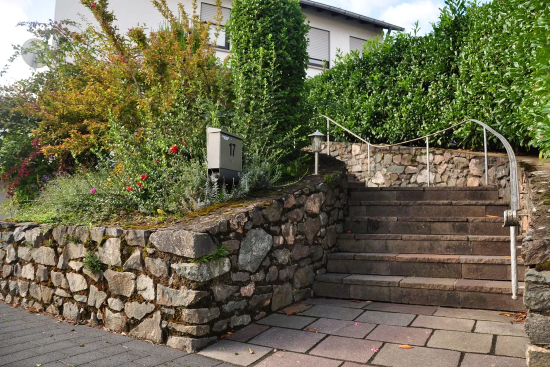 Escalier de jardin en pierre avec main courante métallique, le long d'un muret