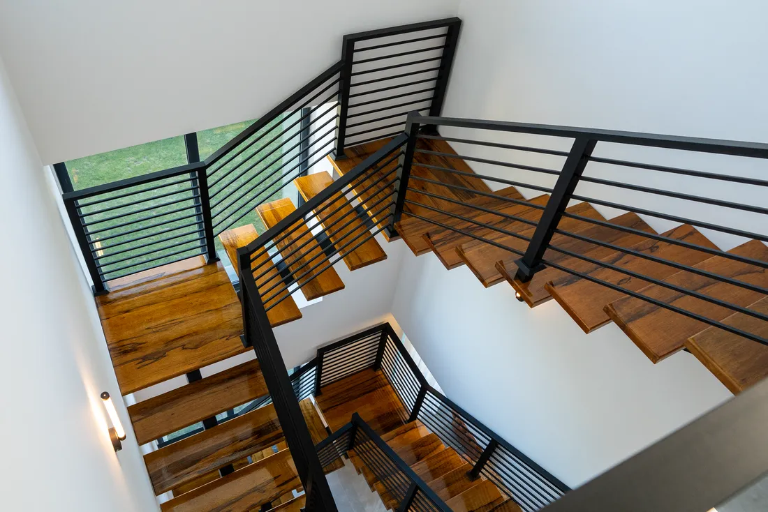 Escalier en bois à garde-corps noir vu d'en haut, dans une maison contemporaine