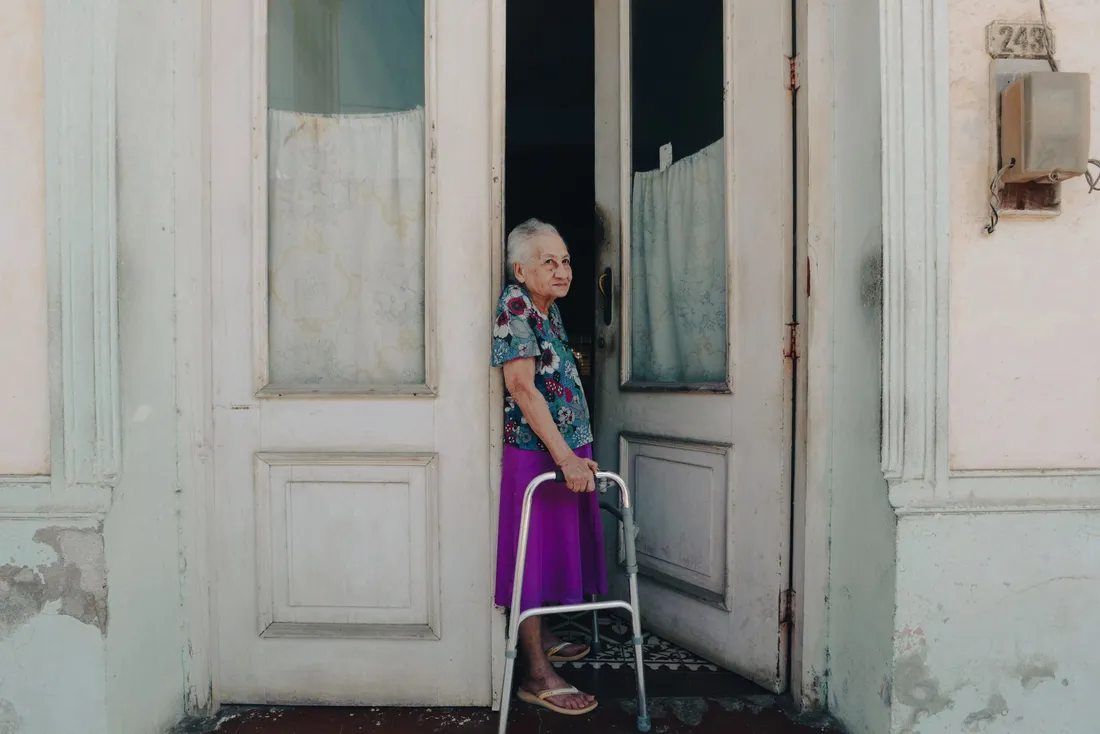Femme âgée avec un déambulateur sur le seuil de sa maison