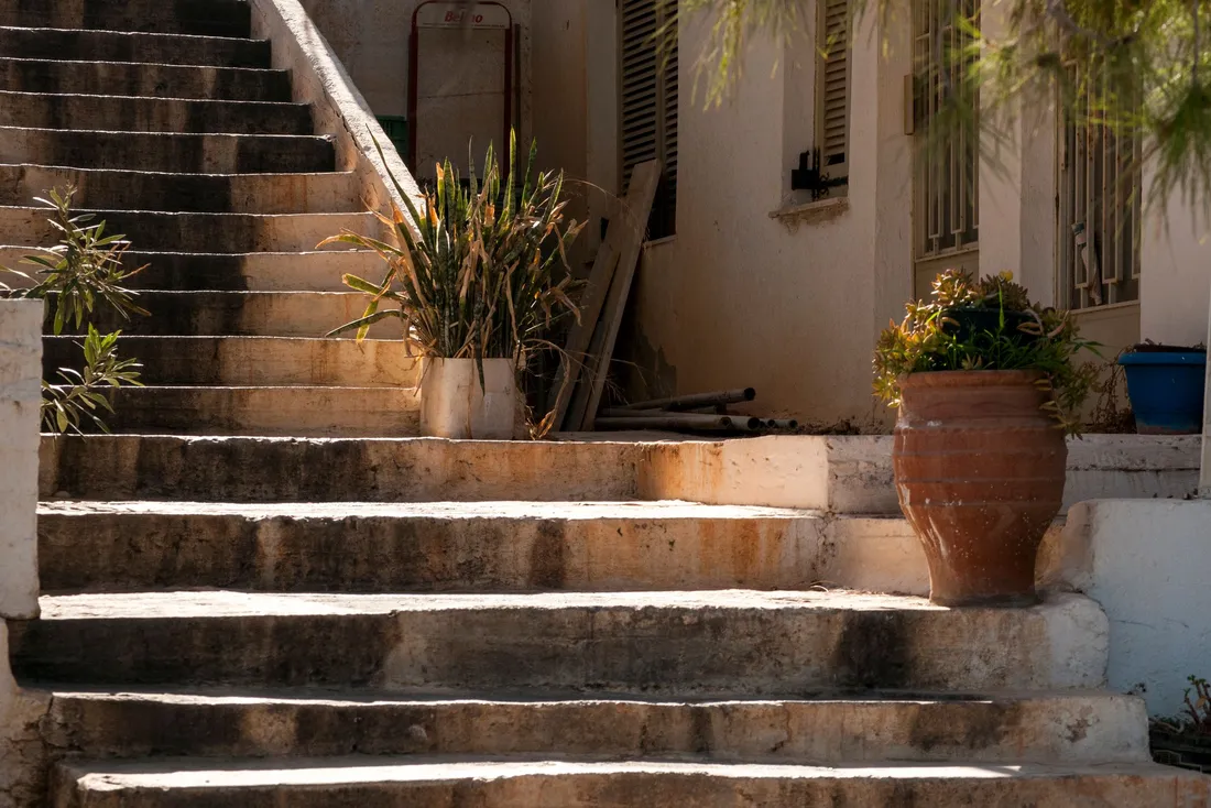 Escalier extérieur en pierre bordé de plantes en pots, devant une maison méditerranéenne